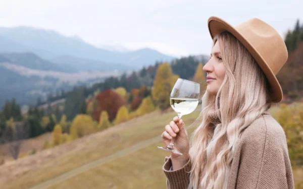 Woman enjoys wine in autumn mountains.