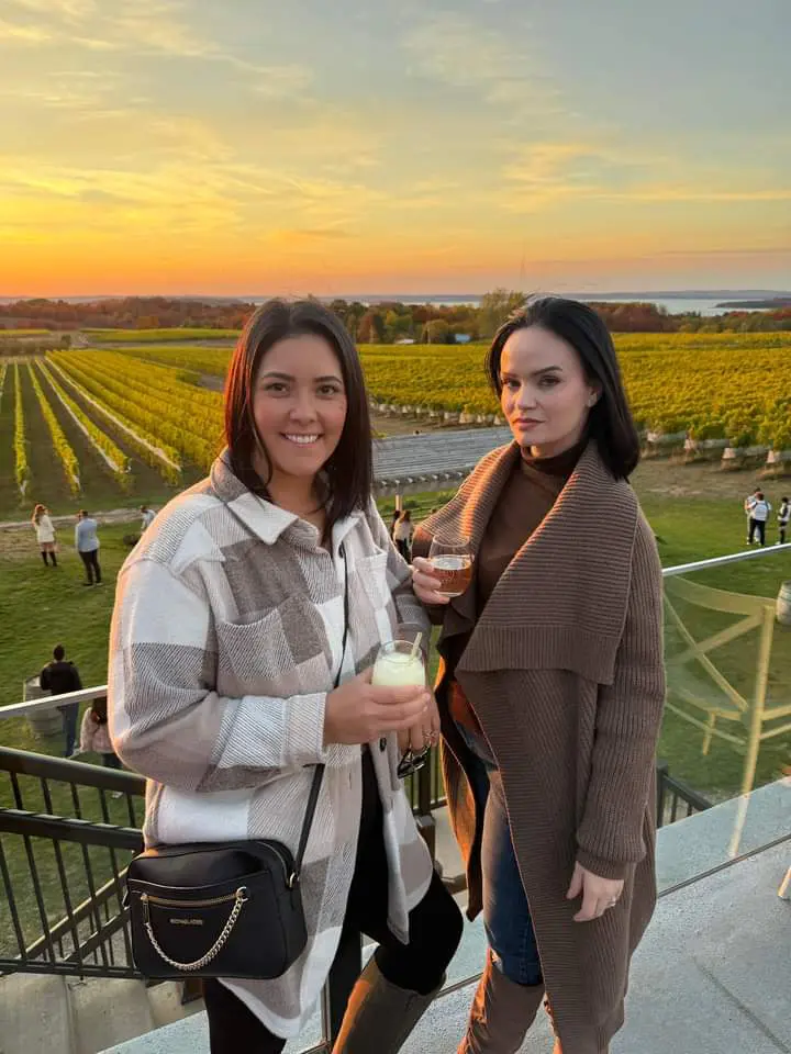 Friends enjoying wine at sunset vineyard.