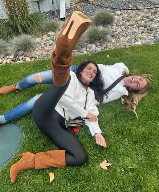 Two women laughing, boots in air.